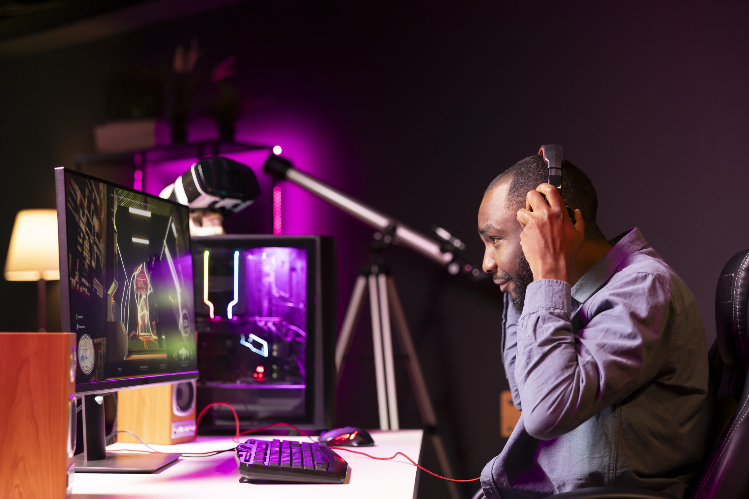 Professional gamer competing in intense online multiplayer videogame, streaming live from vibrant living room with neon lights. Man using gaming PC and headphones for immersive experience